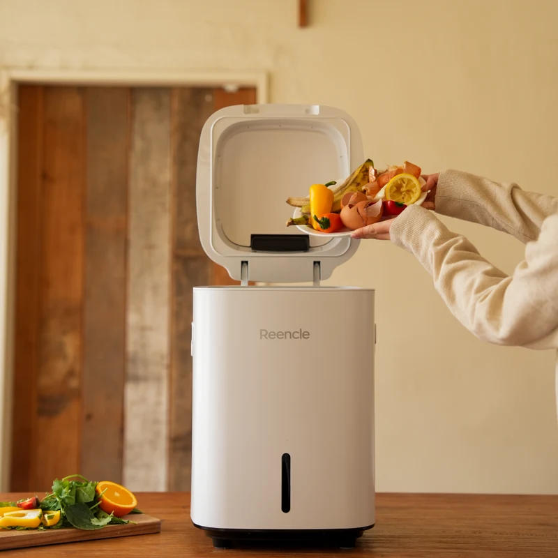 White Reencle Prime electric composter receiving food scraps